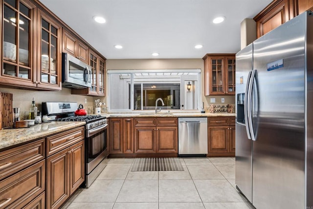 kitchen featuring light stone counters, appliances with stainless steel finishes, light tile patterned flooring, and sink