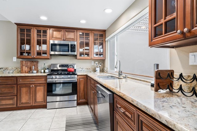 kitchen featuring stainless steel appliances, light stone countertops, sink, and light tile patterned floors