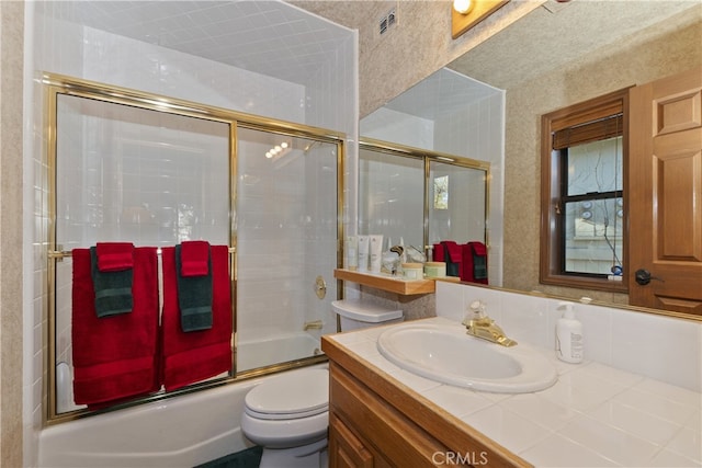 full bathroom featuring vanity, enclosed tub / shower combo, and toilet