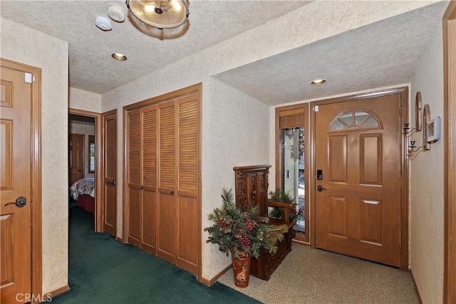 carpeted foyer entrance featuring a textured ceiling