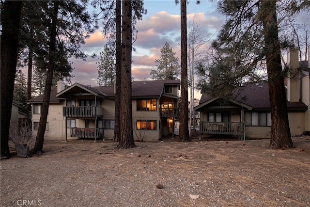 back house at dusk featuring a balcony