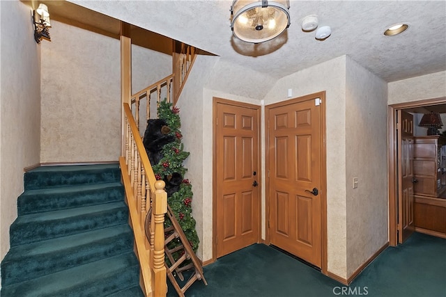 foyer featuring a textured ceiling and dark colored carpet