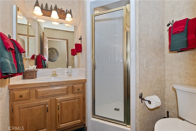 bathroom with vanity, toilet, and a shower with door