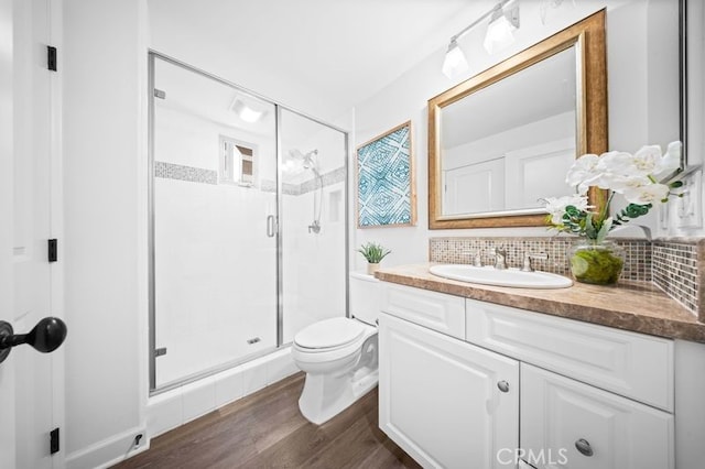 bathroom with hardwood / wood-style flooring, vanity, an enclosed shower, decorative backsplash, and toilet