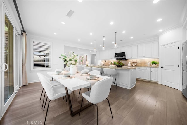 dining space featuring crown molding, sink, and hardwood / wood-style flooring