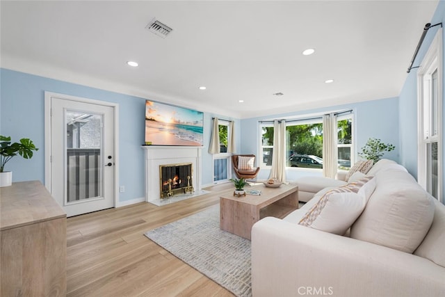 living room featuring a high end fireplace and light hardwood / wood-style flooring