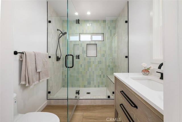 bathroom with vanity, hardwood / wood-style floors, a shower with door, and toilet