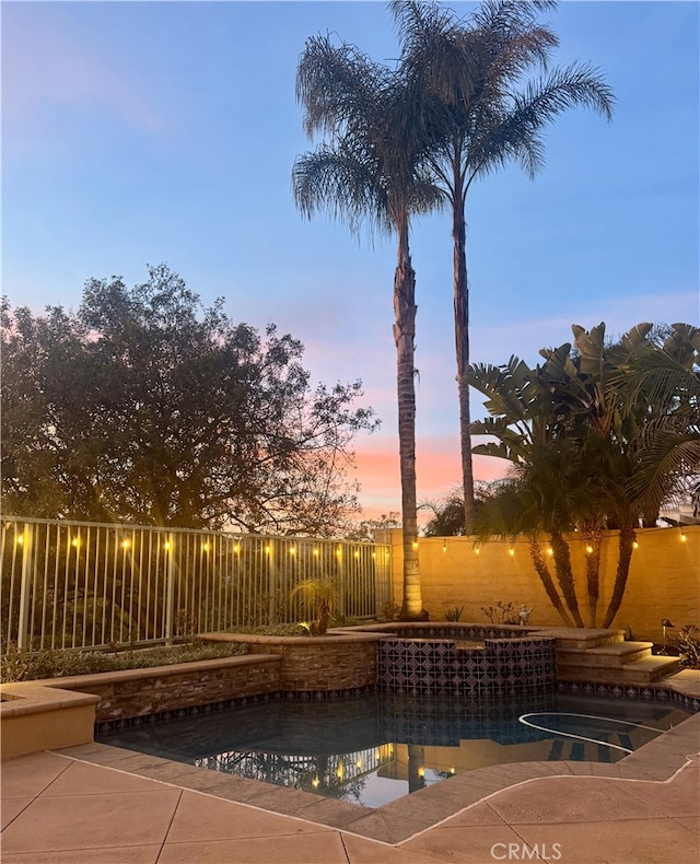 pool at dusk with a fenced in pool and a fenced backyard