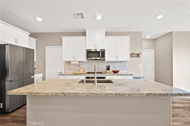 kitchen featuring white cabinetry, stainless steel appliances, and a center island with sink