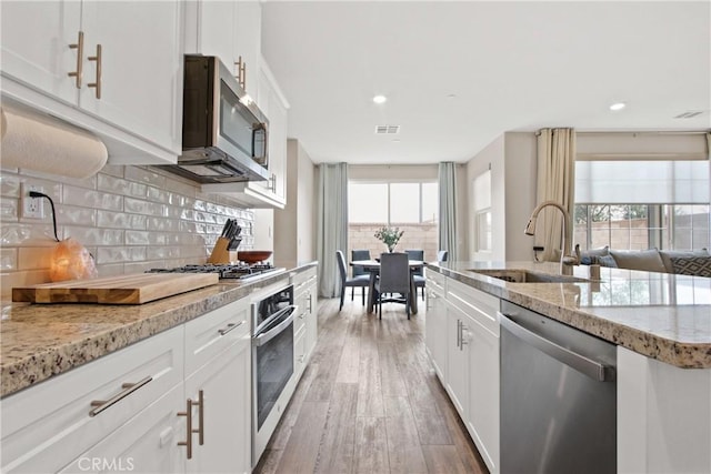 kitchen with stainless steel appliances, sink, white cabinets, and decorative backsplash