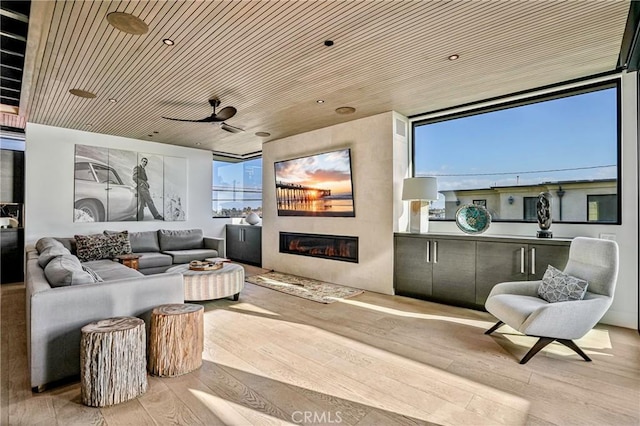 cinema featuring ceiling fan, light hardwood / wood-style flooring, wooden ceiling, and a healthy amount of sunlight