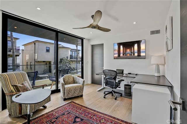 office area with light hardwood / wood-style flooring, floor to ceiling windows, and ceiling fan