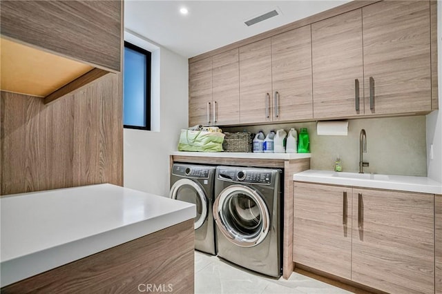 clothes washing area featuring cabinets, independent washer and dryer, and sink