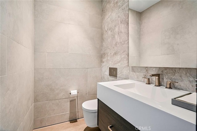 bathroom with vanity, toilet, and tile walls