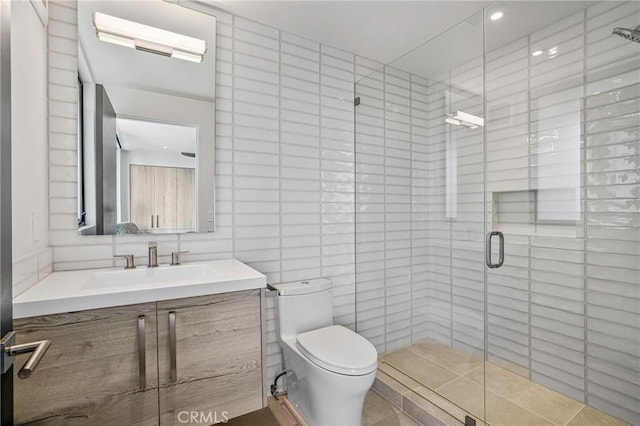 bathroom with vanity, toilet, an enclosed shower, and tile walls