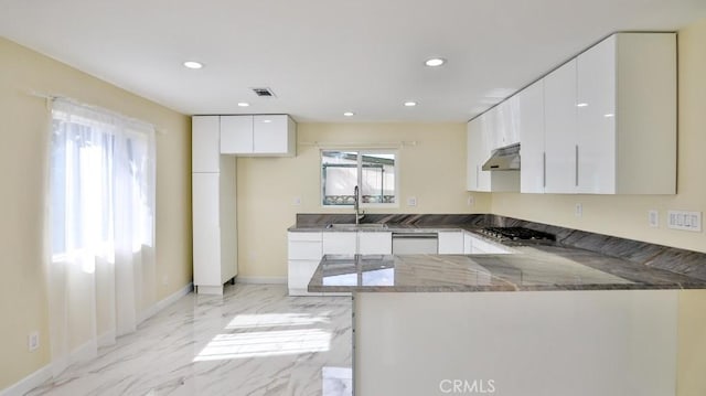 kitchen featuring sink, dark stone countertops, kitchen peninsula, stainless steel gas stovetop, and white cabinets