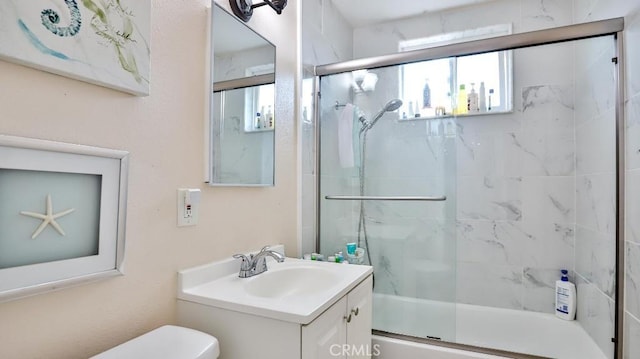 full bathroom featuring vanity, bath / shower combo with glass door, and toilet