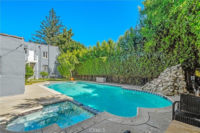 view of pool with a pool with connected hot tub, fence, and a patio