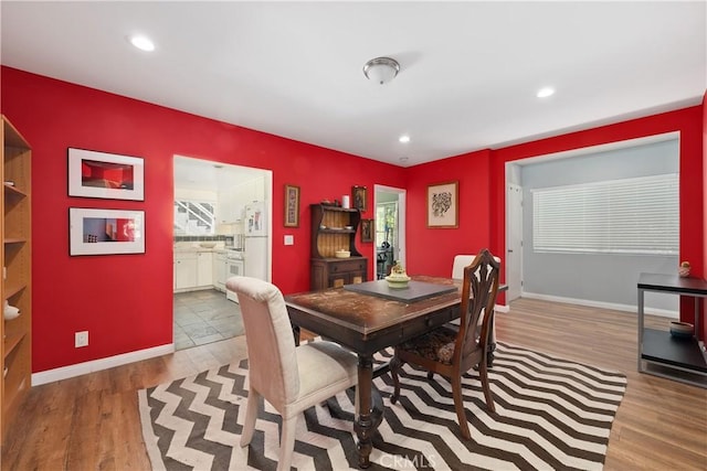 dining space with baseboards, wood finished floors, and recessed lighting