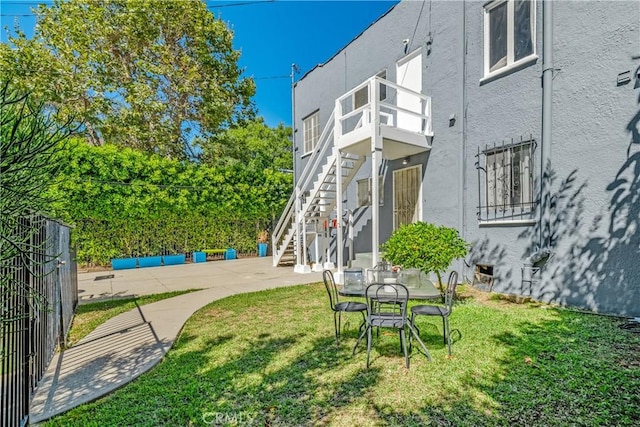 view of yard with stairs, a patio, fence, and a balcony