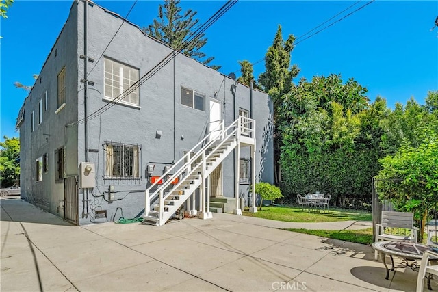 rear view of house with a patio, stairway, and stucco siding