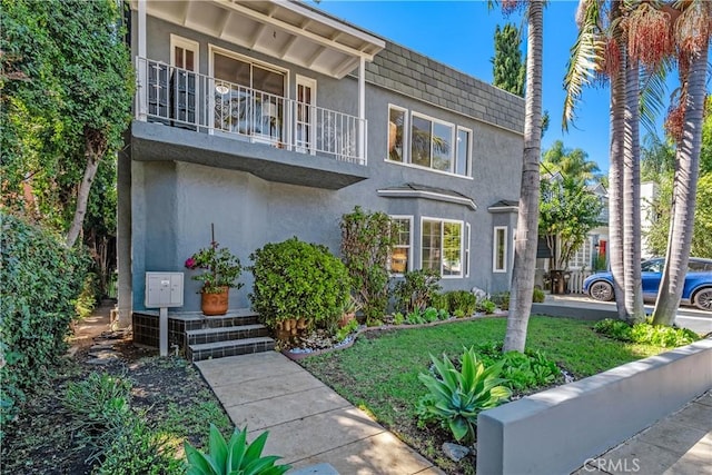 view of front facade featuring a balcony and a front yard