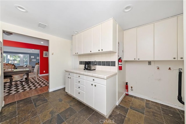 kitchen featuring tile counters, white cabinets, and stone tile flooring