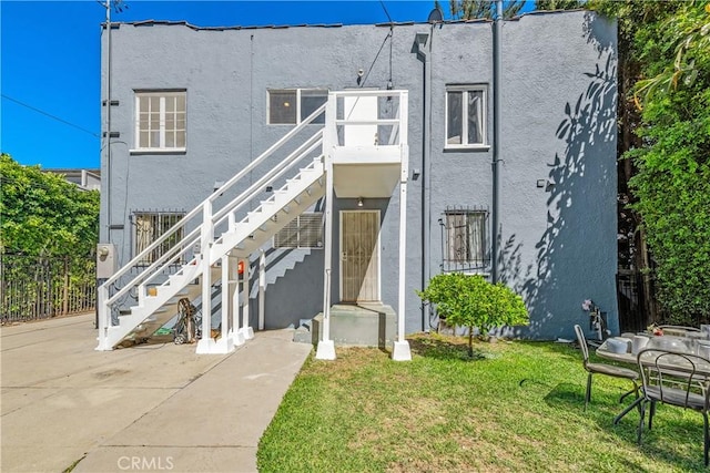 view of front of property with stairway, a front lawn, and stucco siding