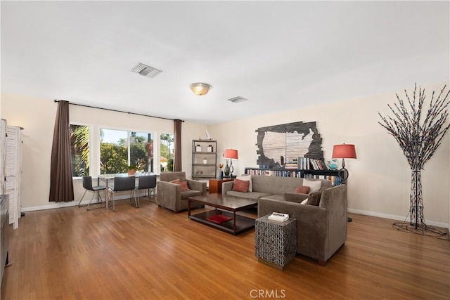 living area with wood finished floors, visible vents, and baseboards