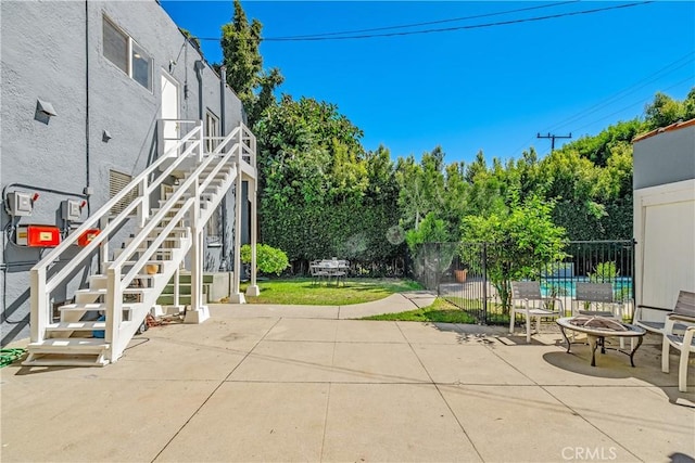 view of patio / terrace featuring a fire pit, stairway, and fence