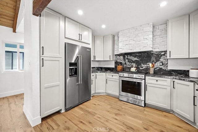 kitchen featuring white cabinetry, appliances with stainless steel finishes, and dark stone counters