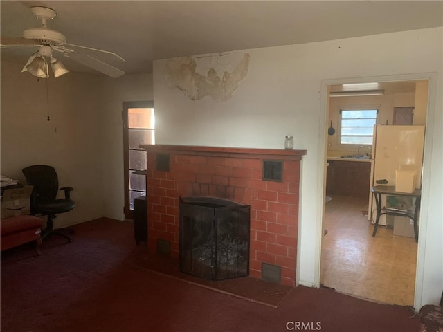 living room with ceiling fan, sink, and a fireplace