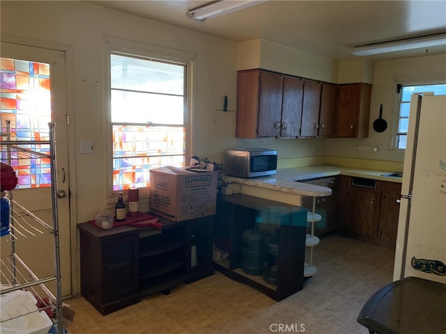 kitchen with light parquet floors, white fridge, and dark brown cabinetry