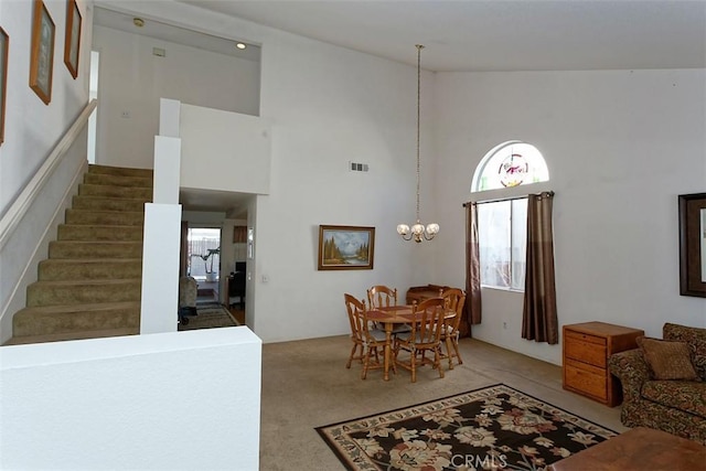 living room with high vaulted ceiling, light colored carpet, and an inviting chandelier