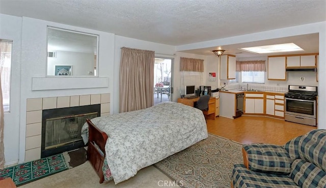 bedroom with a tiled fireplace, sink, and a textured ceiling