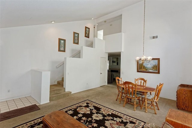 carpeted dining area featuring a tile fireplace, an inviting chandelier, and high vaulted ceiling