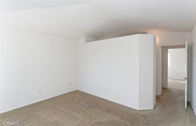 carpeted spare room featuring lofted ceiling