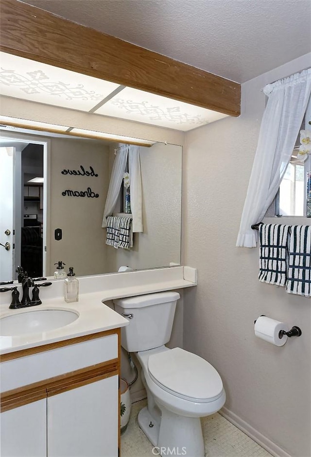 bathroom with vanity, toilet, beam ceiling, and a textured ceiling