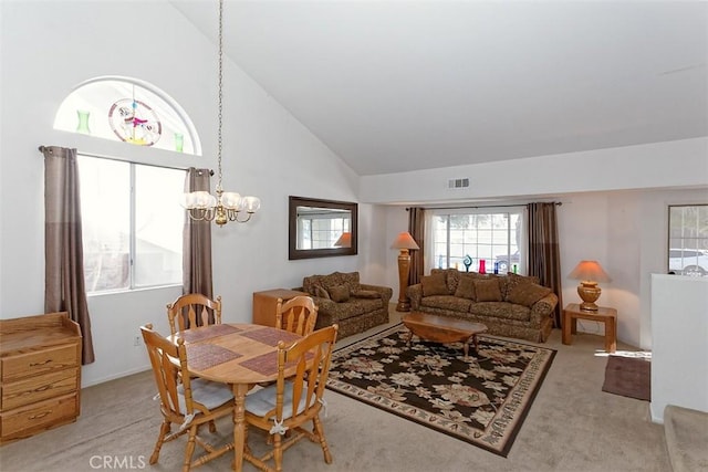 carpeted dining space featuring high vaulted ceiling and a chandelier