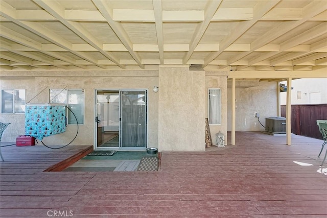 view of exterior entry featuring a wooden deck and central AC unit