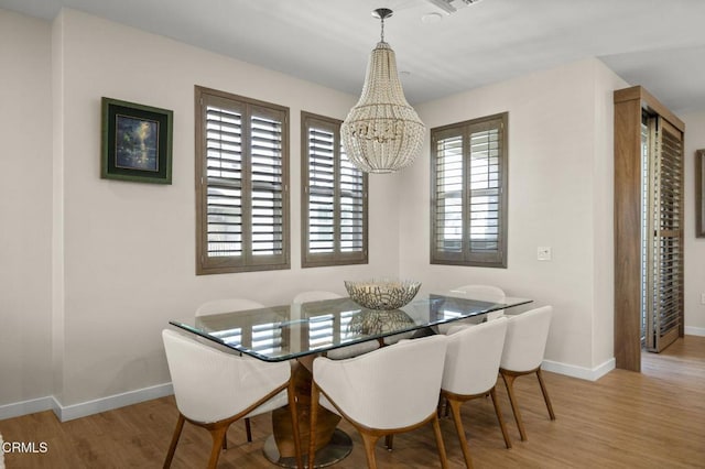 dining space with a notable chandelier and light hardwood / wood-style flooring