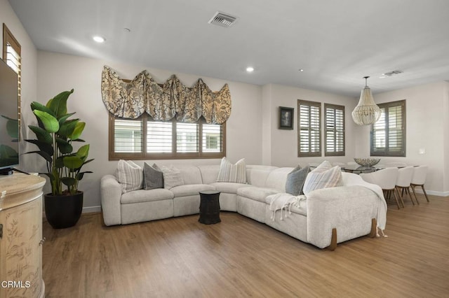 living room featuring an inviting chandelier, plenty of natural light, and light hardwood / wood-style flooring