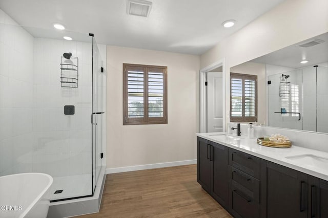 bathroom with wood-type flooring, a wealth of natural light, vanity, and plus walk in shower