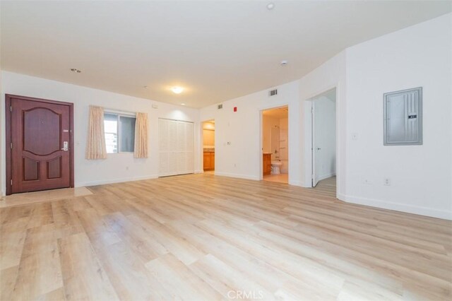 unfurnished living room with electric panel and light wood-type flooring