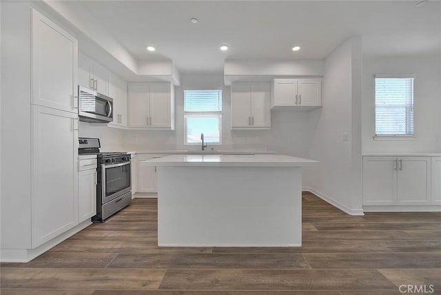 kitchen featuring stainless steel appliances, a kitchen island, dark wood-type flooring, and white cabinets