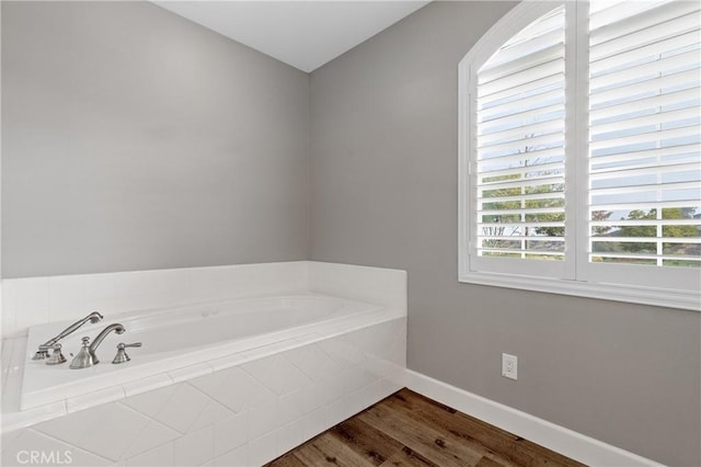 bathroom with baseboards, a bath, and wood finished floors