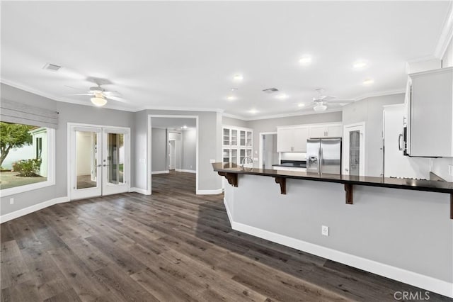 kitchen with a ceiling fan, stainless steel fridge with ice dispenser, dark countertops, a breakfast bar, and french doors