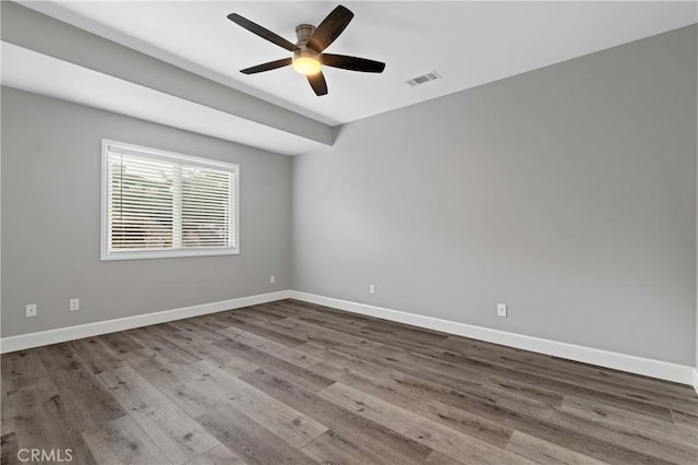 empty room featuring visible vents, ceiling fan, baseboards, and wood finished floors