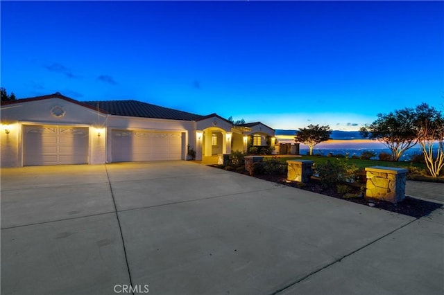 view of front of property featuring concrete driveway, an attached garage, a tiled roof, and stucco siding