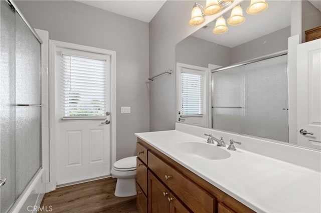 full bathroom featuring bath / shower combo with glass door, vanity, toilet, and wood finished floors